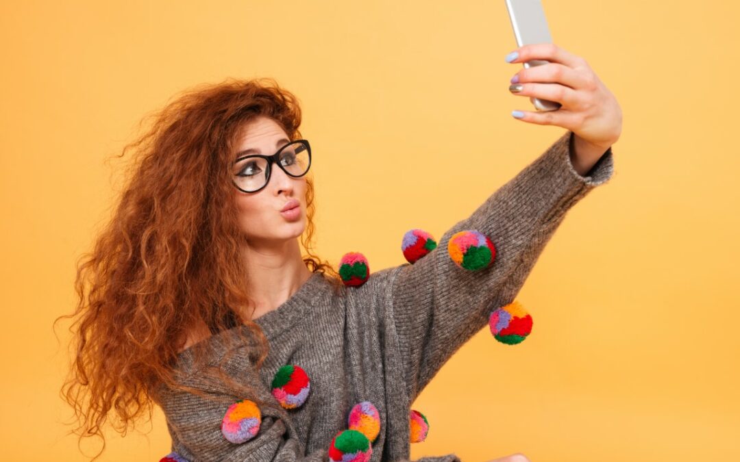 Woman with long red hair taking selfie photo on smartphone